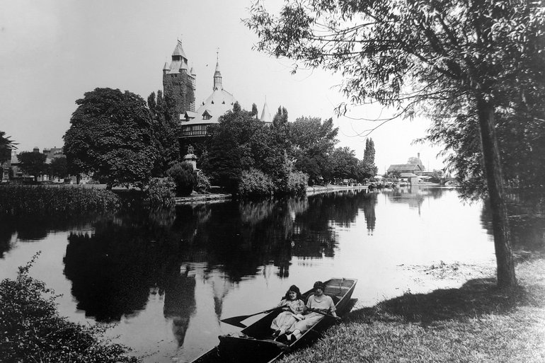 Two girls reclining in a rowing boat in the River Avon in front of The Shakespeare Memorial Theatre.