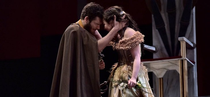 Two characters (Laertes saying farewell to Ophelia?) stand with their heads close together, each with their right hand holding the back of the other's head. The man wears a cloak, the lady a fur-collared low-cut dress; she carries some flowers in her left hand.