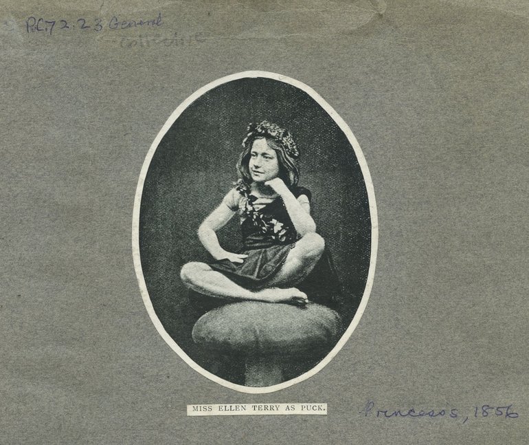 She sits cross-legged on a mushroom, her right hand on her hip, her left elbow on her left knee and her hand resting against her chin. She has long wavy hair and a circlet of flowers on her head; she wears a loose tunic but is bare-footed.