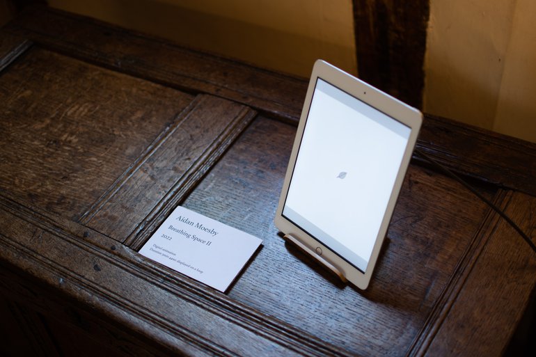 The installation of Breathing Space II at Anne Hathaway's Cottage. An iPad stands on top of a dark wooden chest playing an animation of various tree leaves.
