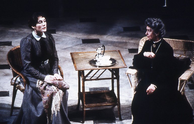 Two seated ladies confront each other across a small tea-table with a single tea or coffee pot and a single cup on a tray.