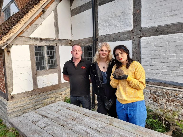 An image of Sophie and Kyra from Hedgehog friendly town, releasing a hedgehog at Mary Arden's Farm.