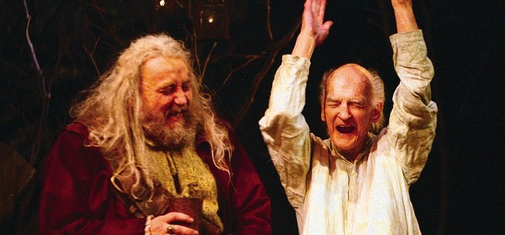 Falstaff has a red gown, shaggy long almost-white hair, and a short brown beard, he holds a tankard. Justice Silence wears a white shirt, and has his hands upraised, his eyes closed, and his mouth open.