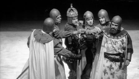 Six armed men stand in a close semi-circle, their right-hands joined in the centre. The bearded man at the end on the right wears a surcoat with the French arms; the man third from the left has a crown over his helmet.