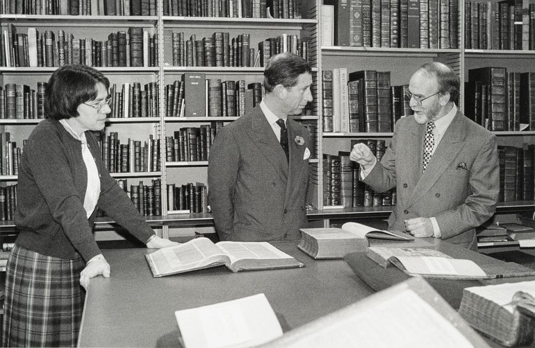 A black and white photo of King Charles III in the Shakespeare Birthplace Trust Collections, viewing what appears to be a copy of Shakespeare's First Folio