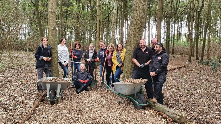 A group of volunteers and Shakespeare Birthplace Trust Gardens staff looking happy after a hard day's work clearing a path through the plantation at Anne Hathaway's Cottage.