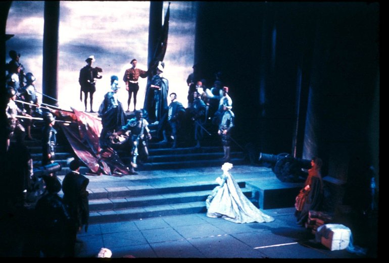 Othello Royal Shakespeare Company Othello, 1961. On a staircase Othello, flanked by a number of nobles on his left and soldiers on his right, approaches Desdemona, dressed in white standing alone at the foot of the steps. Her maids (in red) are some paces behind her.