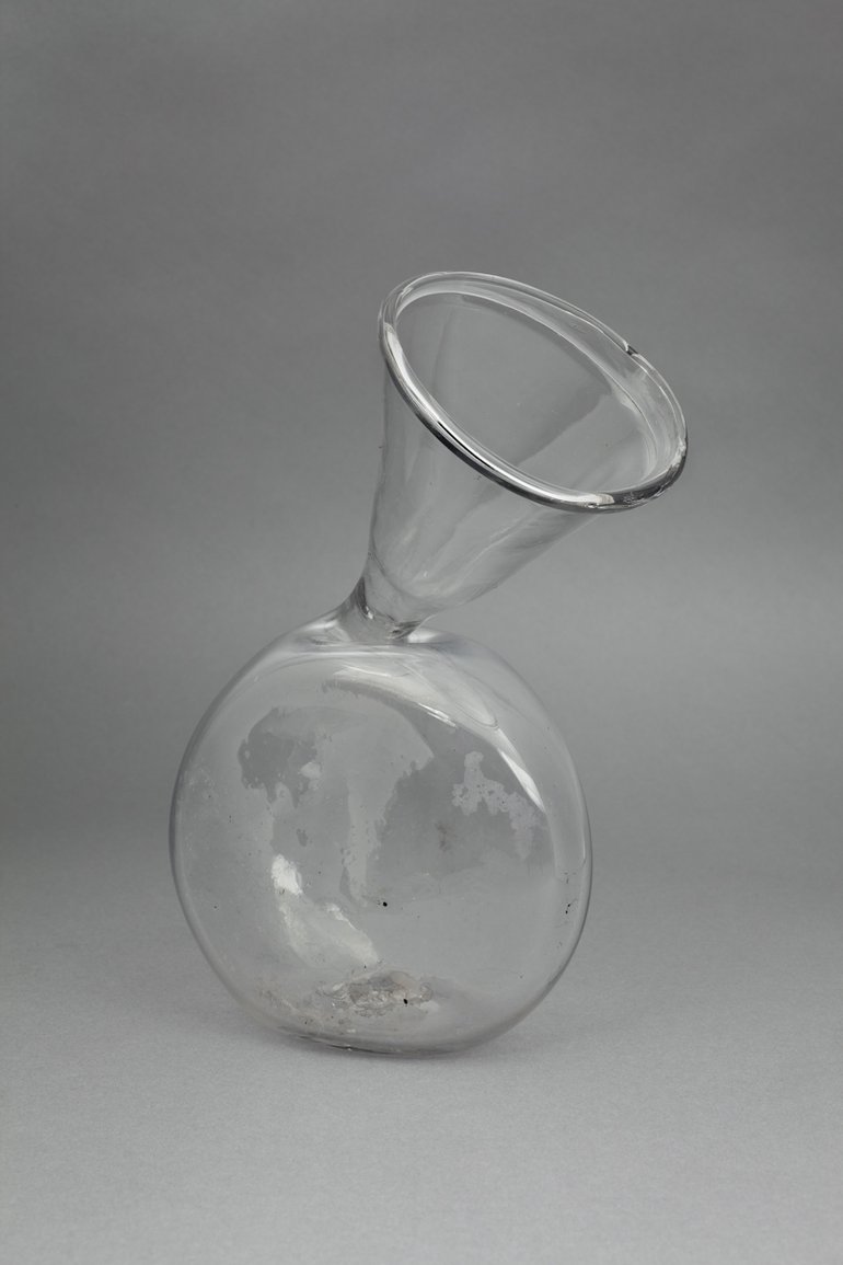 The glass flask has a large round, flat-bottomed globe from the top of which a glass funnel comes up at an angle.