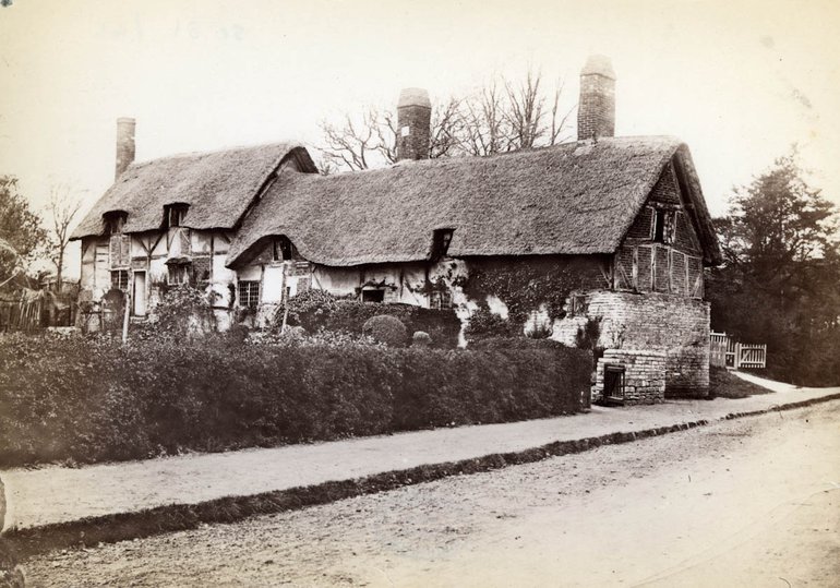 The cottage seen from the road. Although in good physical condition, it has plants growing up it, and it stands in a garden which looks a little neglected.