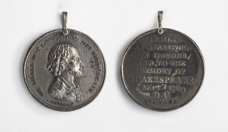 The obverse has an engraving of Shakespeare - high forehead, curly hair, and a short beard. The reverse has an inscription which in the picture is largely illegible, although the words "memory of Shakespeare" can be seen.