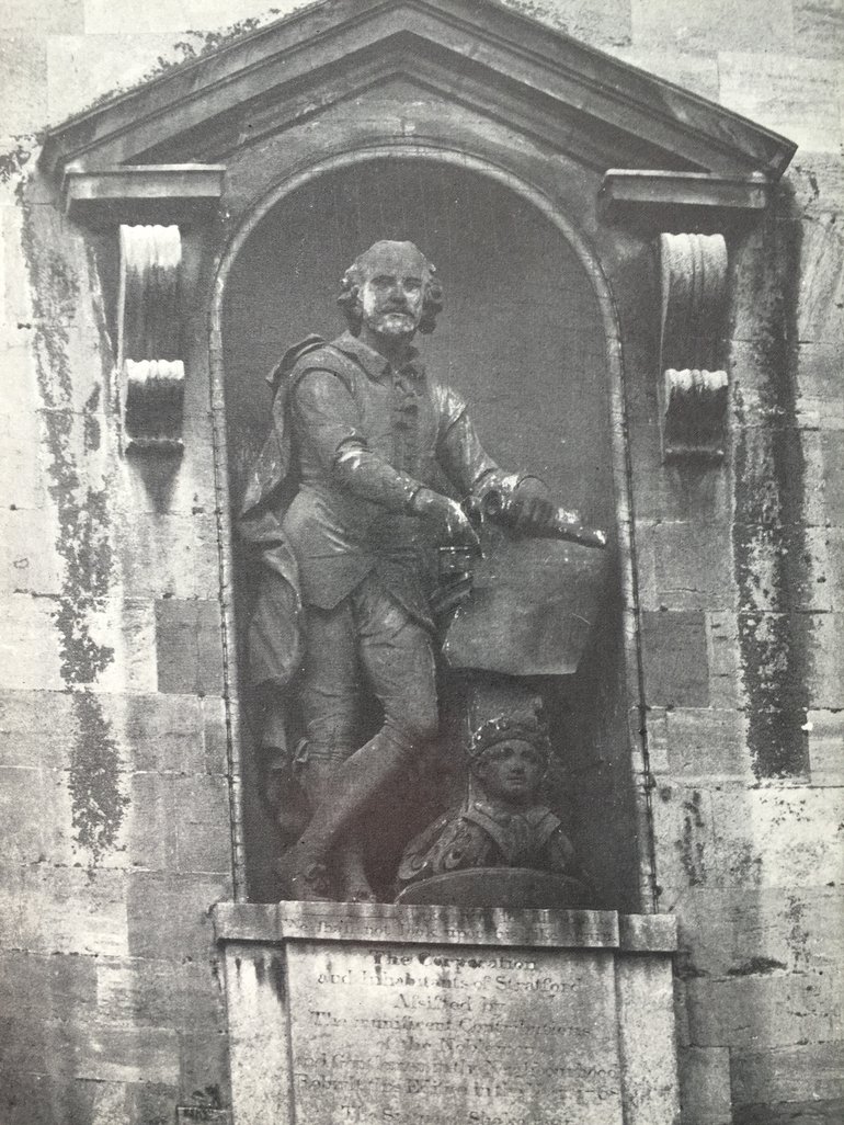 A black and white photo of the statue of William Shakespeare, standing in its niche in Stratford-upon-Avon Town Hall.