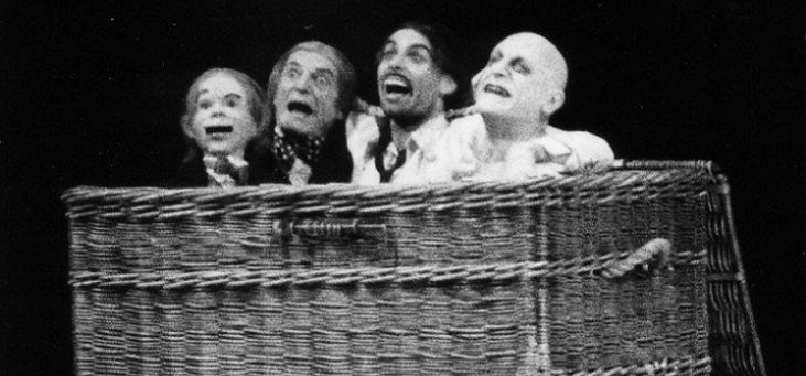 Four figures open-mouthed in horror are squashed together in a basket.